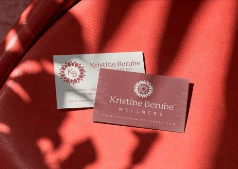 Kristine Berube Wellness business cards on a red fabric background